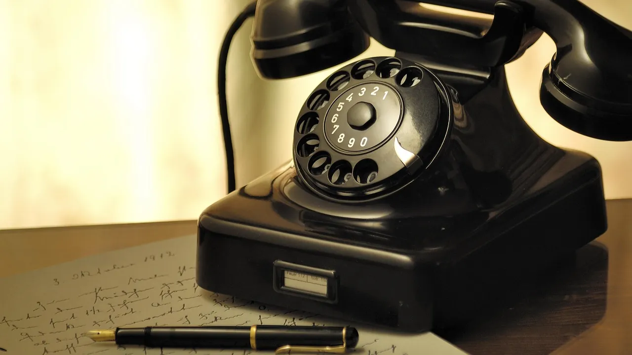 Téléphone noir à disque posé près d'un stylo et d'une lettre manuscrite