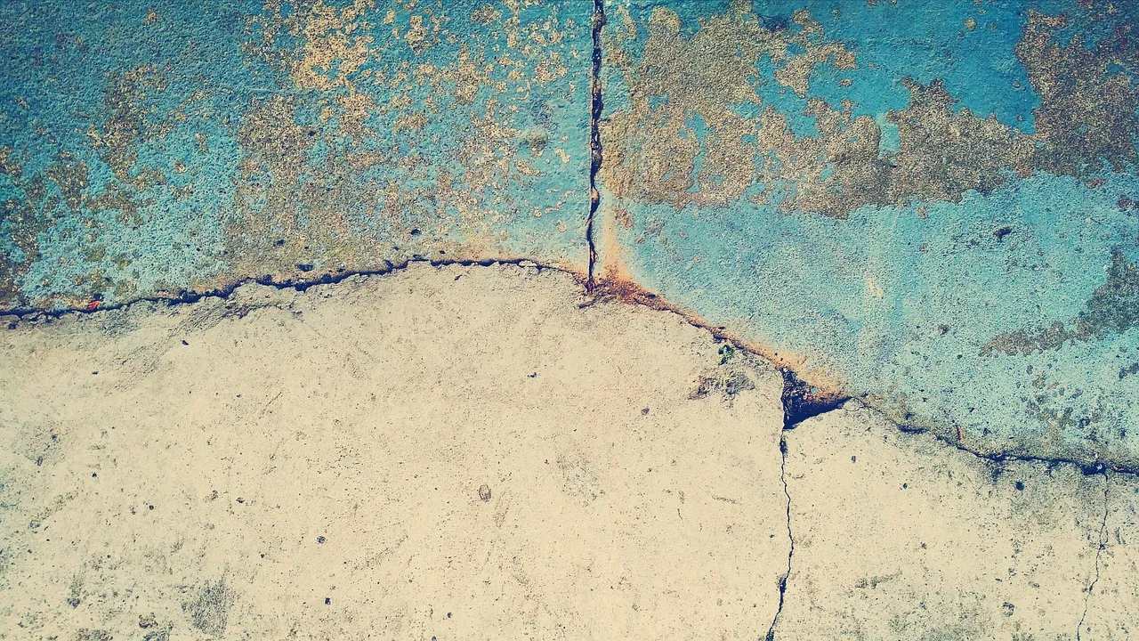 Dalle de béton fendue laissant voir des éclats de peinture turquoise